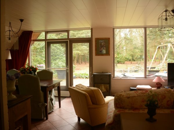 Huiskamer met links grote eettafel en houtkachel